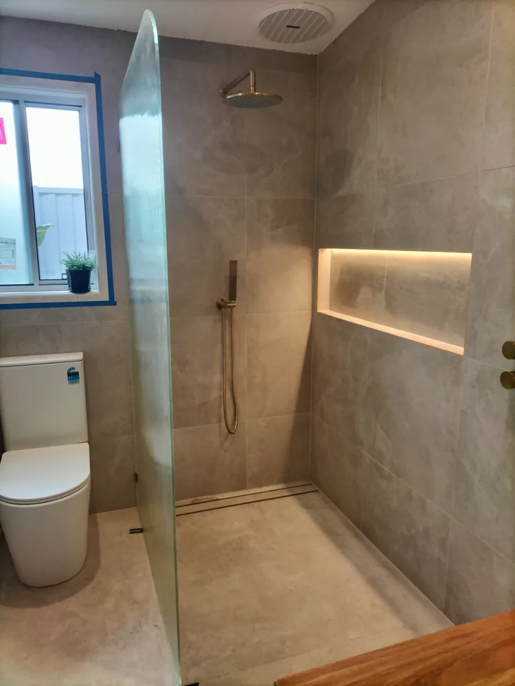 Bathroom renovation with a walk-in shower and polished concrete finish, a Seaforth Builders project on the Gold Coast