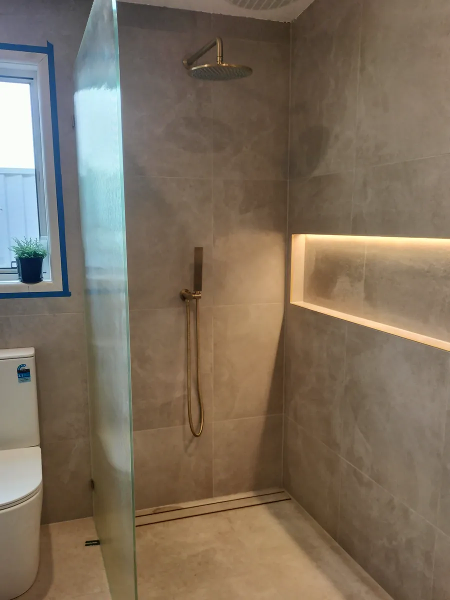 Bathroom renovation with a curved shower screen and polished concrete finish, a Seaforth Builders project on the Gold Coast